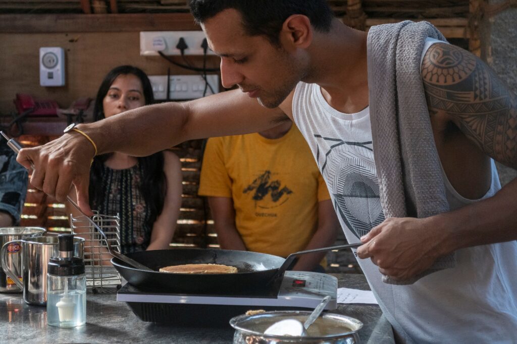 Shek making a vegan pancake in the tea hut with different people watching