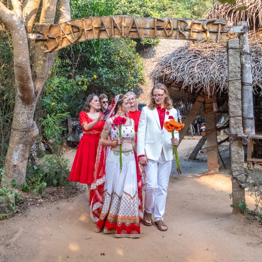 Wedding couple walking through the Sadhana Forest entrance under the Sadhana forest sign